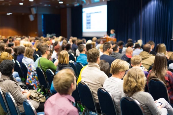Audience in lecture hall participating at business event.
